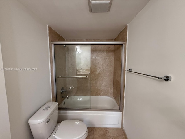 bathroom featuring bath / shower combo with glass door, tile patterned floors, and toilet