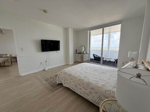 bedroom featuring access to exterior, light hardwood / wood-style floors, and expansive windows