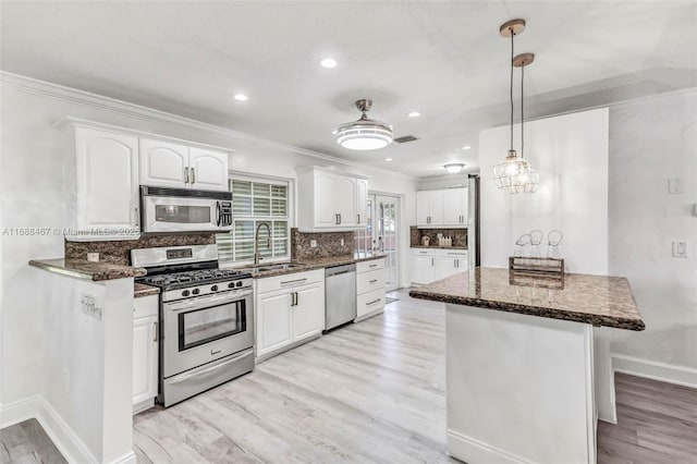 kitchen featuring white cabinets, decorative light fixtures, stainless steel appliances, and sink