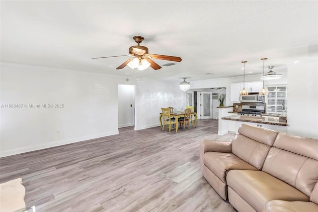 living room with ceiling fan and light wood-type flooring