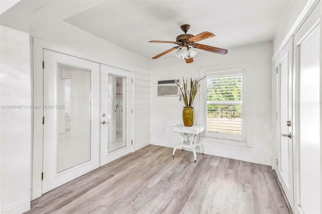 interior space with a wall mounted air conditioner, french doors, light wood-type flooring, and ceiling fan