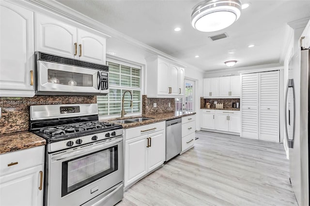 kitchen featuring white cabinets, sink, stainless steel appliances, and dark stone countertops