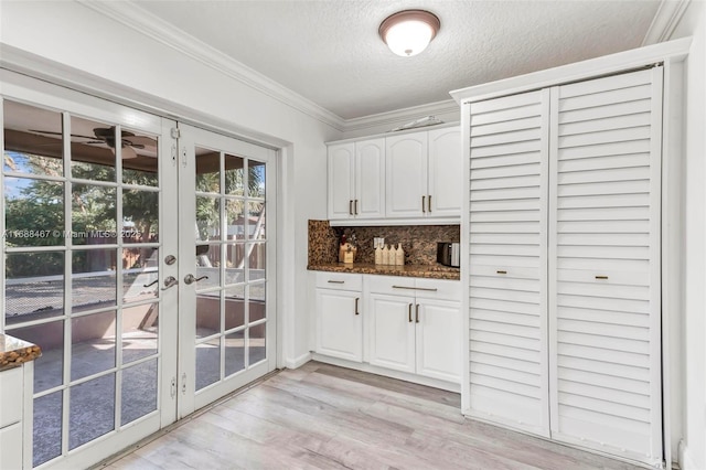 bar with backsplash, french doors, white cabinets, dark stone countertops, and a textured ceiling