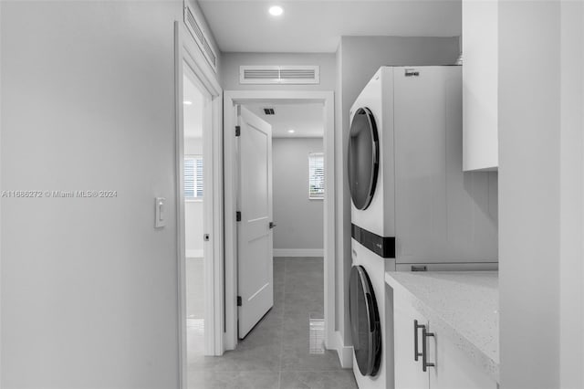 washroom with cabinets, light tile patterned floors, and stacked washer and dryer