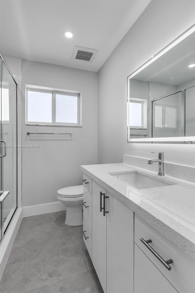 bathroom featuring vanity, a healthy amount of sunlight, an enclosed shower, and toilet