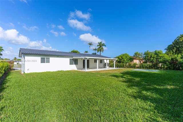 rear view of property featuring a yard and a patio area