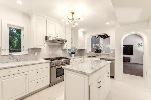 kitchen with a kitchen island, white cabinetry, stainless steel appliances, sink, and light stone counters