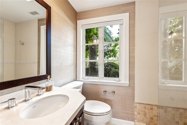 bathroom with tile walls, toilet, and vanity