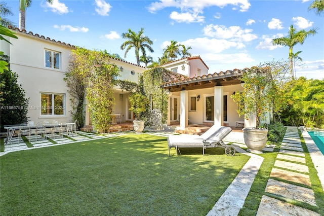 back of property featuring a patio area and a lawn