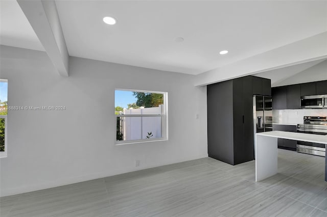 kitchen featuring appliances with stainless steel finishes, tasteful backsplash, and lofted ceiling