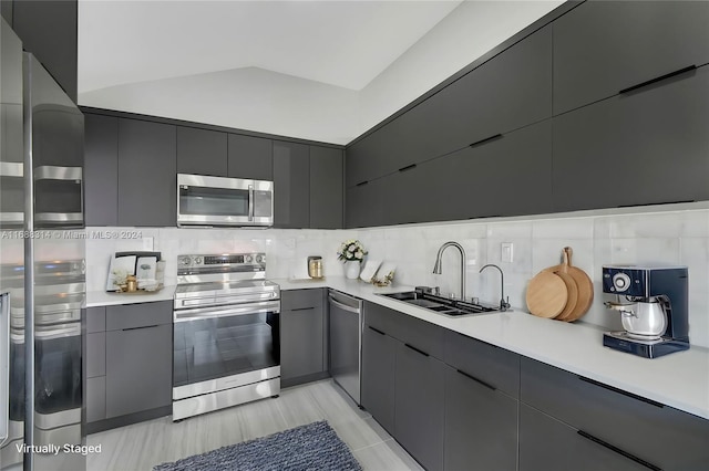 kitchen featuring decorative backsplash, sink, stainless steel appliances, and vaulted ceiling