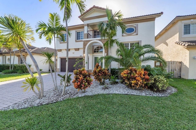 mediterranean / spanish house with a garage, a balcony, and a front yard