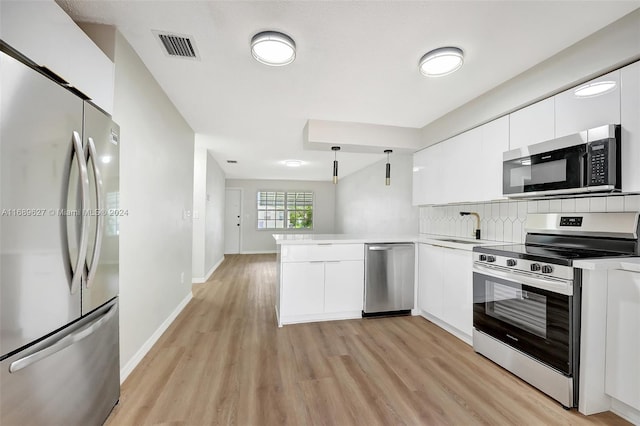 kitchen with kitchen peninsula, white cabinetry, light wood-type flooring, appliances with stainless steel finishes, and decorative light fixtures