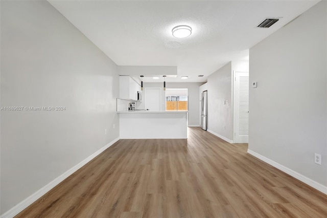 unfurnished living room with a textured ceiling and light hardwood / wood-style flooring