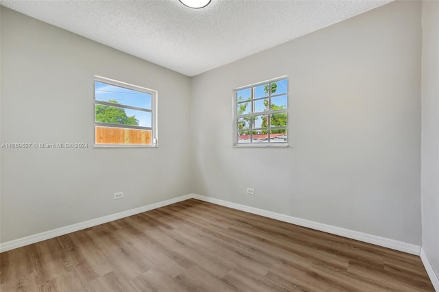 empty room featuring wood-type flooring and a textured ceiling