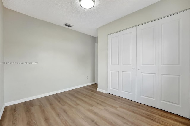 unfurnished bedroom featuring a closet, a textured ceiling, and light hardwood / wood-style floors