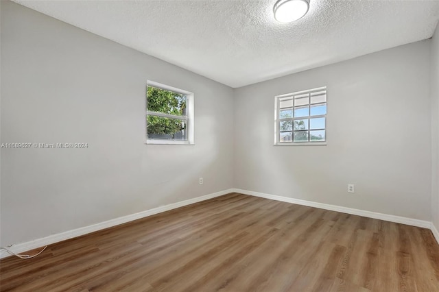 unfurnished room with wood-type flooring and a textured ceiling