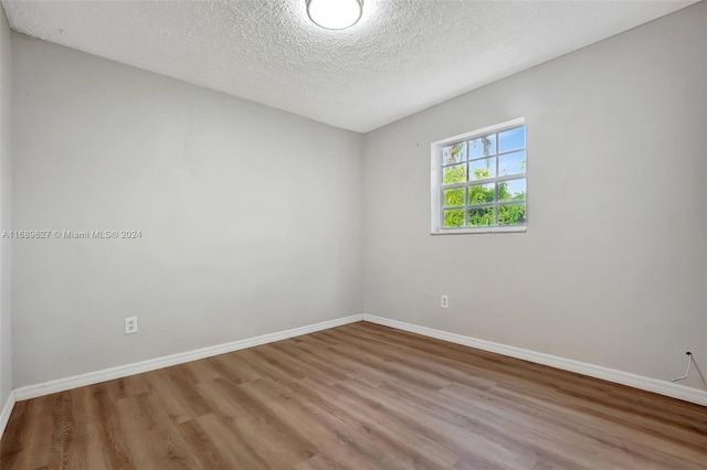 spare room featuring a textured ceiling and light hardwood / wood-style floors