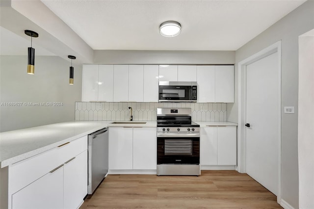 kitchen featuring light hardwood / wood-style floors, pendant lighting, sink, white cabinetry, and appliances with stainless steel finishes