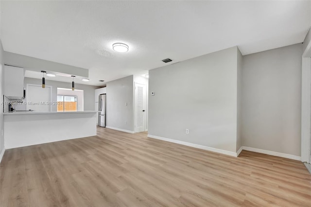 unfurnished living room featuring a textured ceiling and light hardwood / wood-style flooring