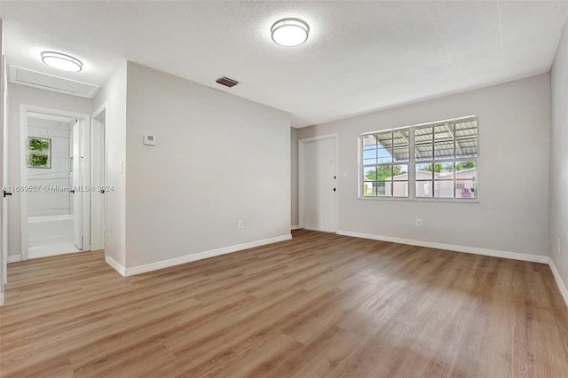 unfurnished room featuring light wood-type flooring and a textured ceiling