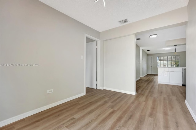 spare room with a textured ceiling and light hardwood / wood-style flooring