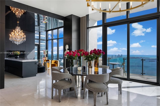 dining room with light tile patterned floors, a water view, a high ceiling, and a wall of windows