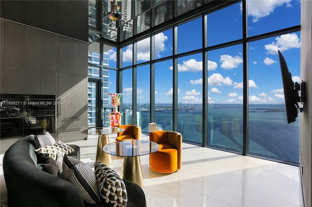 living room with tile patterned floors, a water view, a towering ceiling, and expansive windows