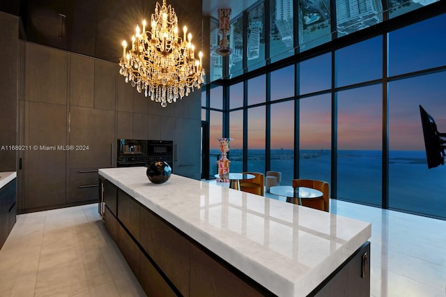 kitchen featuring light tile patterned floors, a center island, a notable chandelier, and a high ceiling