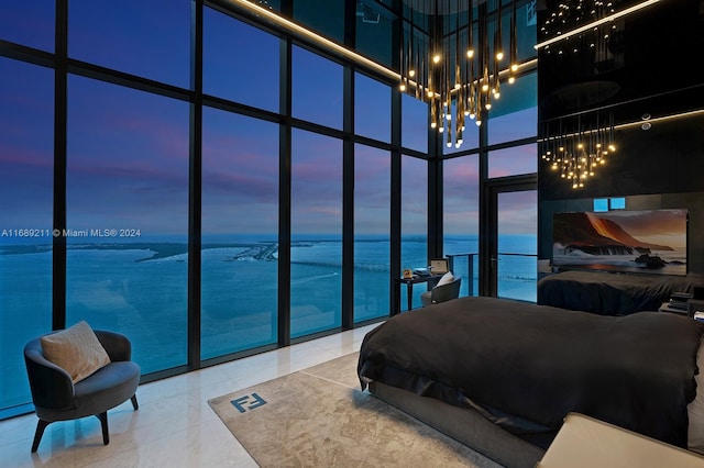 bedroom with tile patterned floors, a towering ceiling, expansive windows, and a notable chandelier