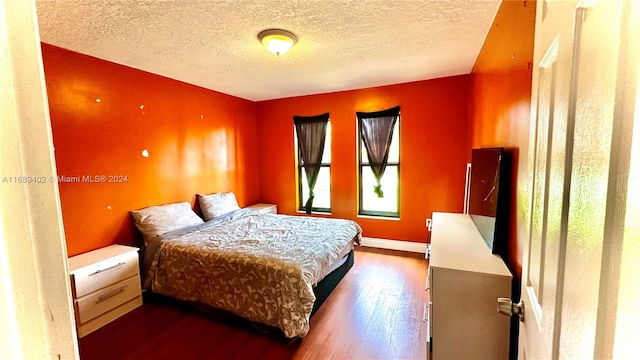 bedroom featuring a textured ceiling and dark hardwood / wood-style floors