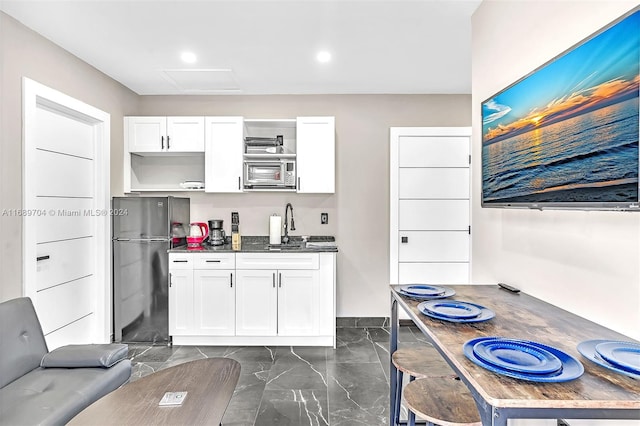 kitchen featuring white cabinets, refrigerator, and sink