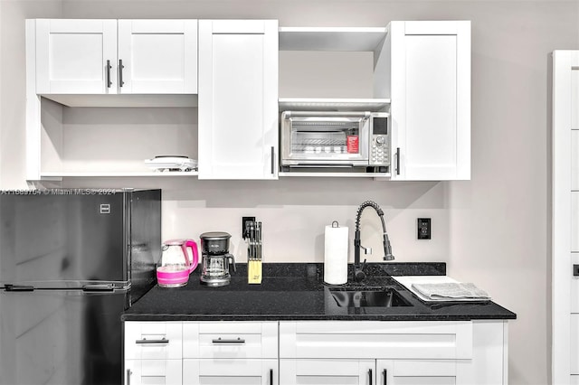 kitchen featuring fridge, sink, and white cabinetry