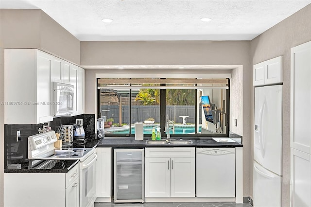 kitchen with sink, a textured ceiling, white appliances, beverage cooler, and white cabinets