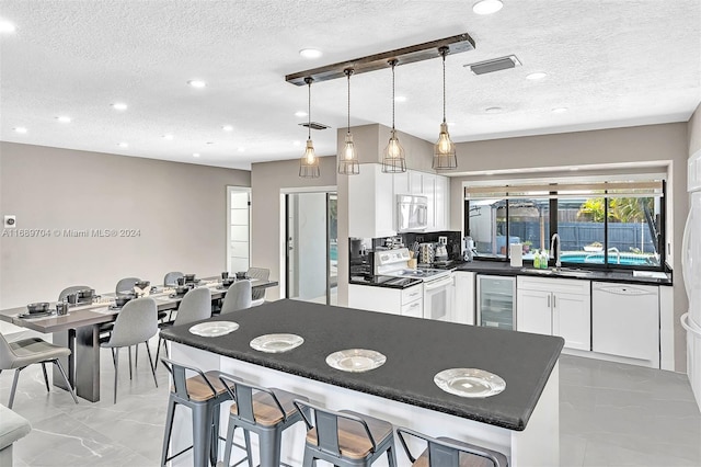 kitchen with sink, decorative light fixtures, white appliances, beverage cooler, and white cabinets