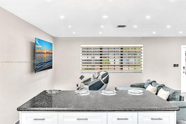 kitchen with dark stone counters and white cabinetry