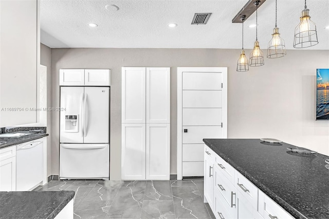 kitchen with white cabinetry, decorative light fixtures, a textured ceiling, dark stone countertops, and white appliances