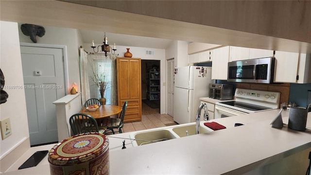 kitchen featuring white cabinetry, white appliances, an inviting chandelier, and kitchen peninsula