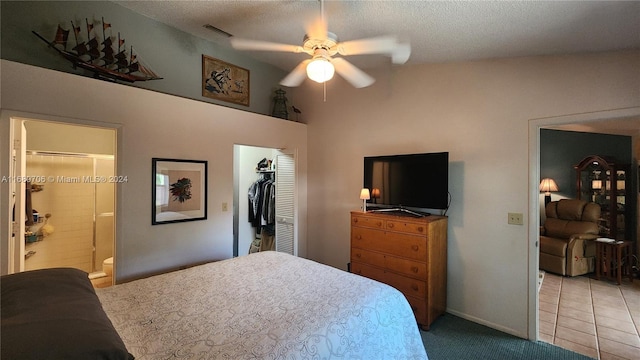 bedroom with a closet, a walk in closet, ensuite bath, a textured ceiling, and ceiling fan