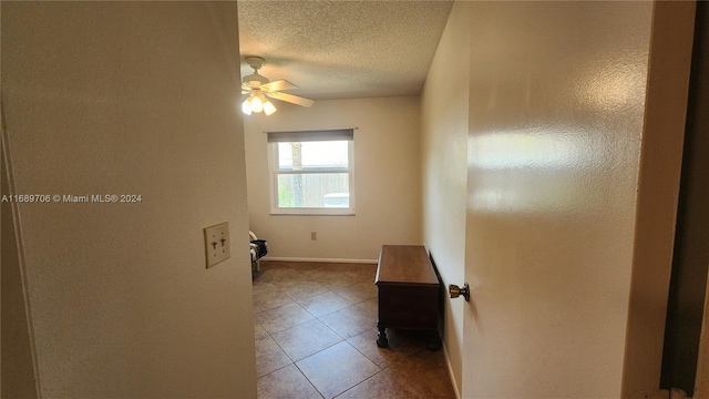 empty room featuring tile patterned floors, a textured ceiling, and ceiling fan