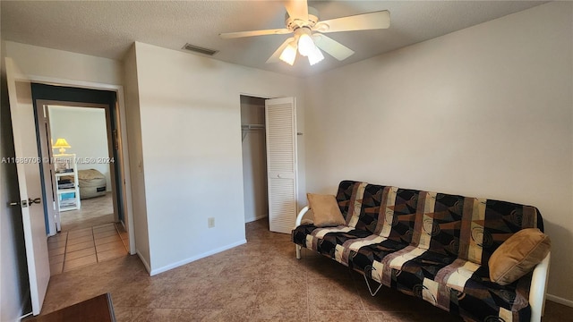 sitting room featuring a textured ceiling, light tile patterned floors, and ceiling fan