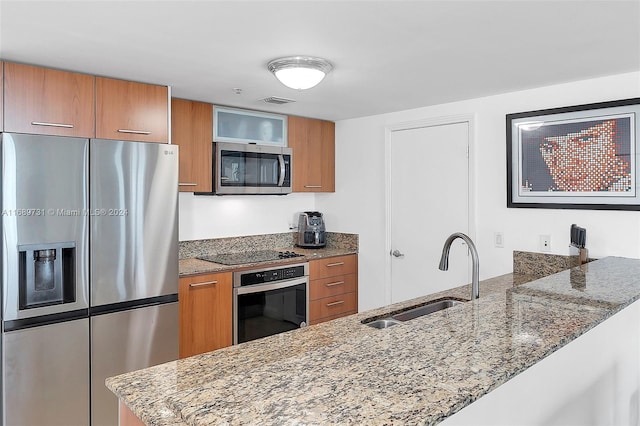 kitchen featuring kitchen peninsula, sink, light stone counters, and stainless steel appliances