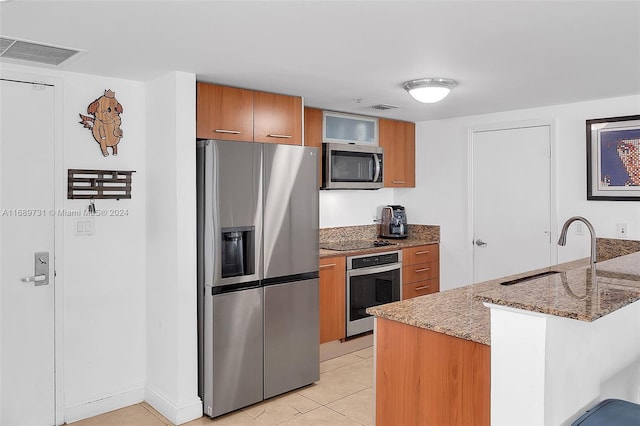 kitchen featuring stainless steel appliances, stone countertops, sink, a kitchen breakfast bar, and light tile patterned floors