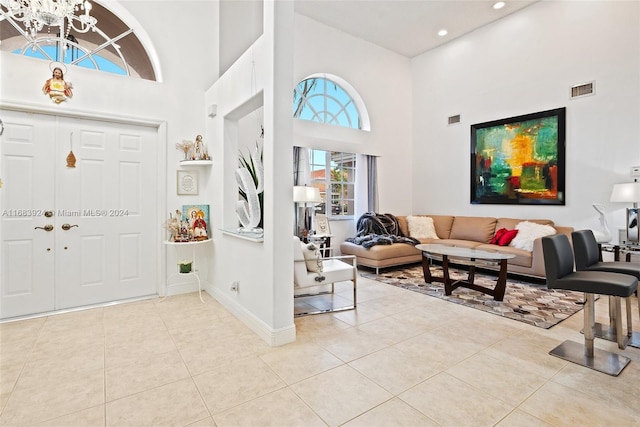 tiled entryway with a high ceiling and a chandelier