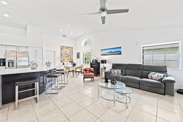 tiled living room featuring ceiling fan, a textured ceiling, and high vaulted ceiling