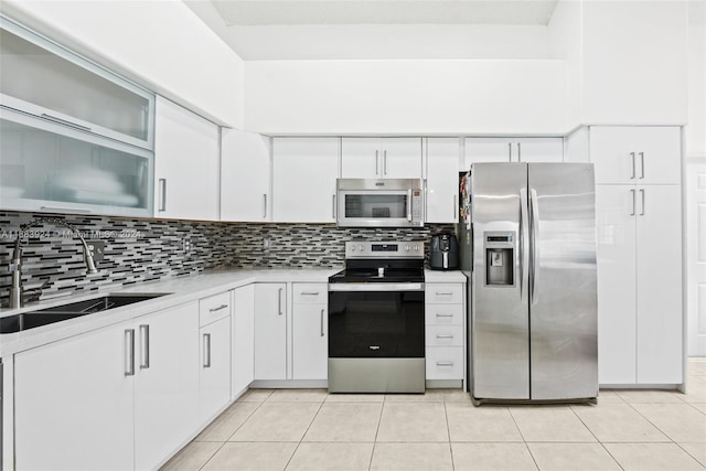 kitchen featuring stainless steel appliances, white cabinets, decorative backsplash, sink, and light tile patterned flooring