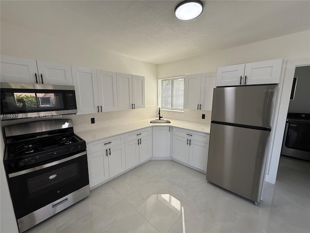 kitchen featuring white cabinetry, appliances with stainless steel finishes, a textured ceiling, backsplash, and sink