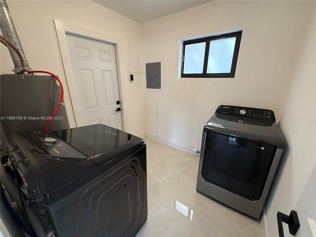 clothes washing area featuring electric panel, light tile patterned floors, and separate washer and dryer