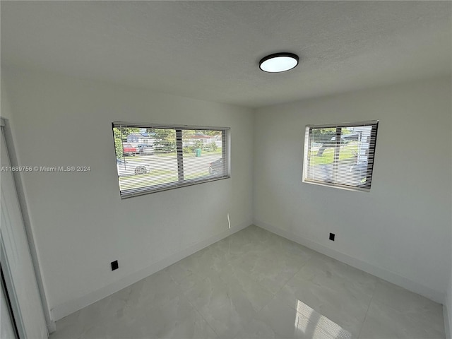 empty room with plenty of natural light and a textured ceiling