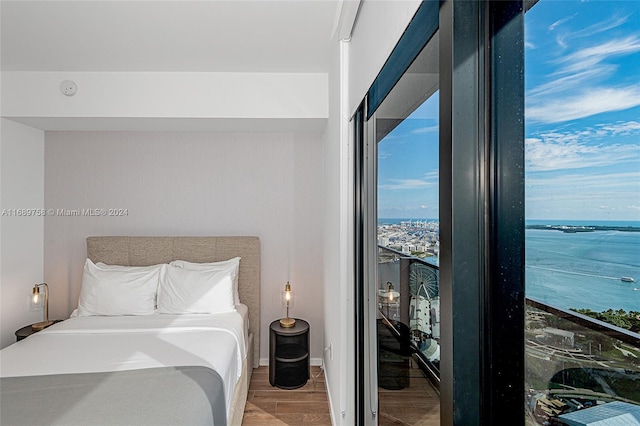 bedroom featuring a water view and hardwood / wood-style flooring